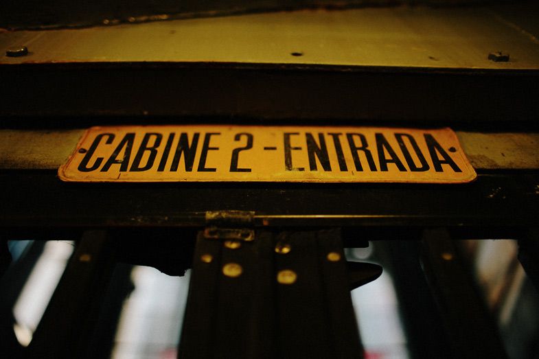 Yellow vintage sign reading 'Cabine 2 - Entrada' in dark lighting.