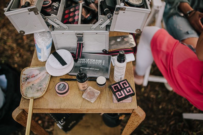 Overhead view of a wooden table with various beauty products and supplies arranged outdoors.