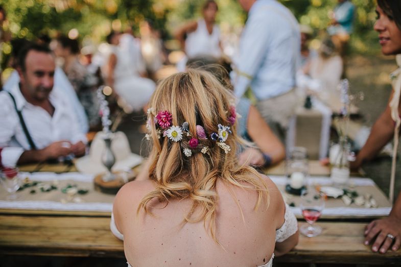A delicate floral crown adorns a wedding guest's hair at an outdoor reception.