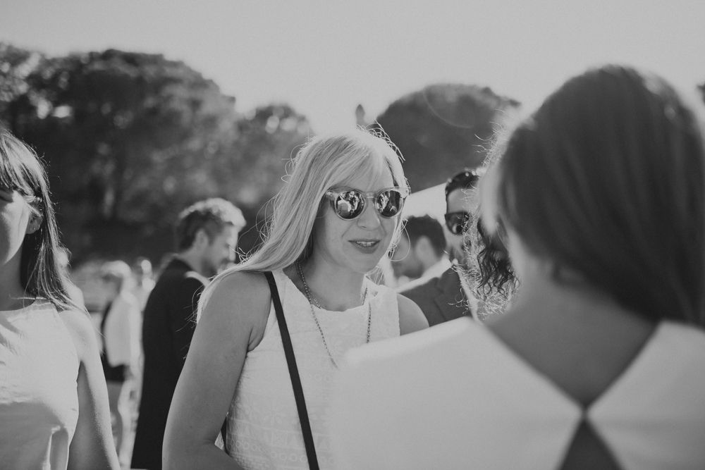 Guests mingling outdoors at a summer wedding celebration in natural lighting.