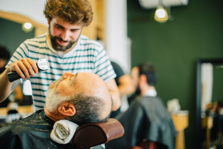 Barber giving a professional haircut in a modern salon with green walls.