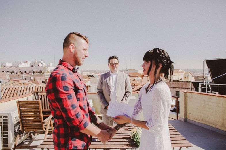 A rooftop ceremony takes place with a couple exchanging vows under bright sunlight.