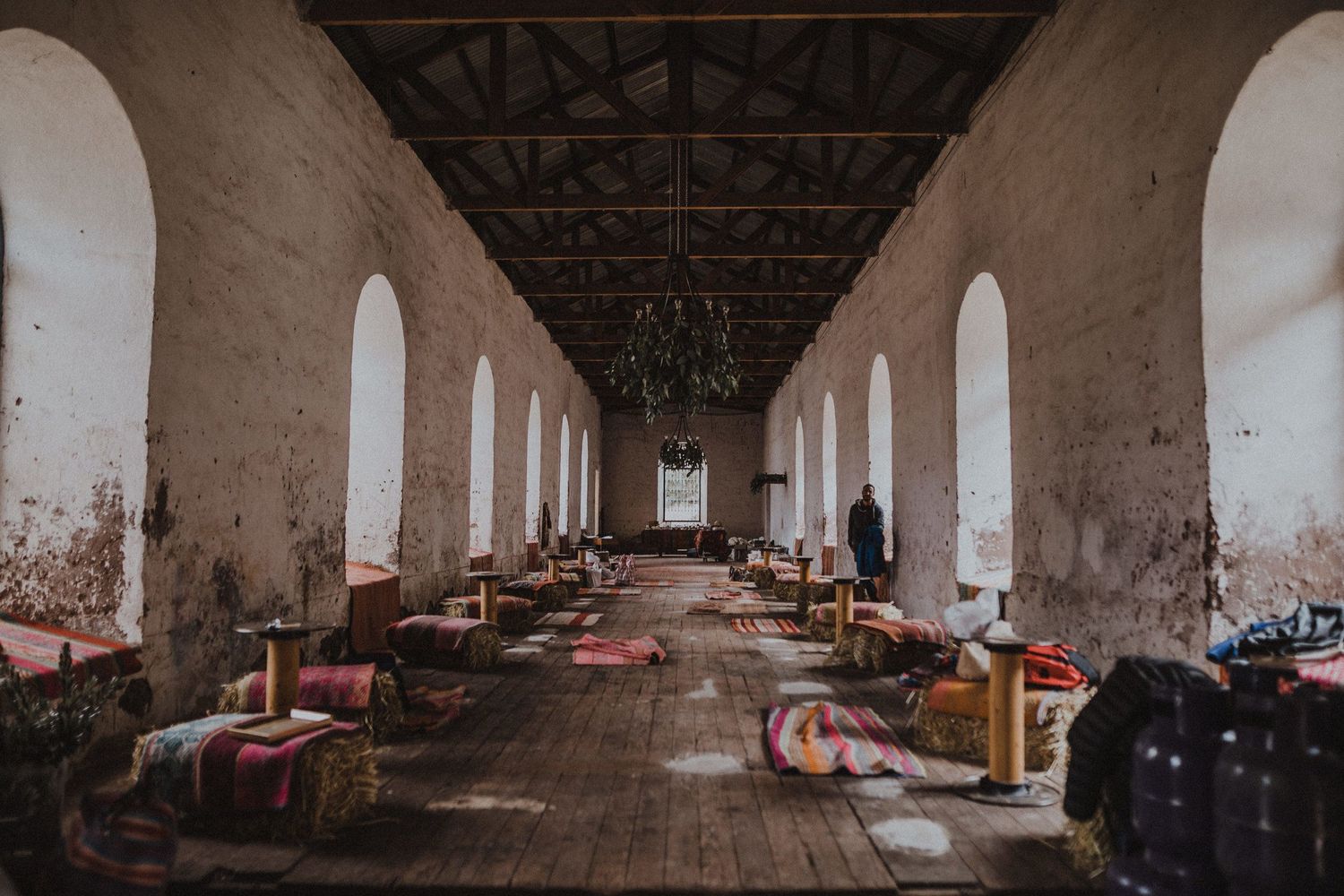 Long interior hallway with arched columns and scattered belongings on wooden floor.