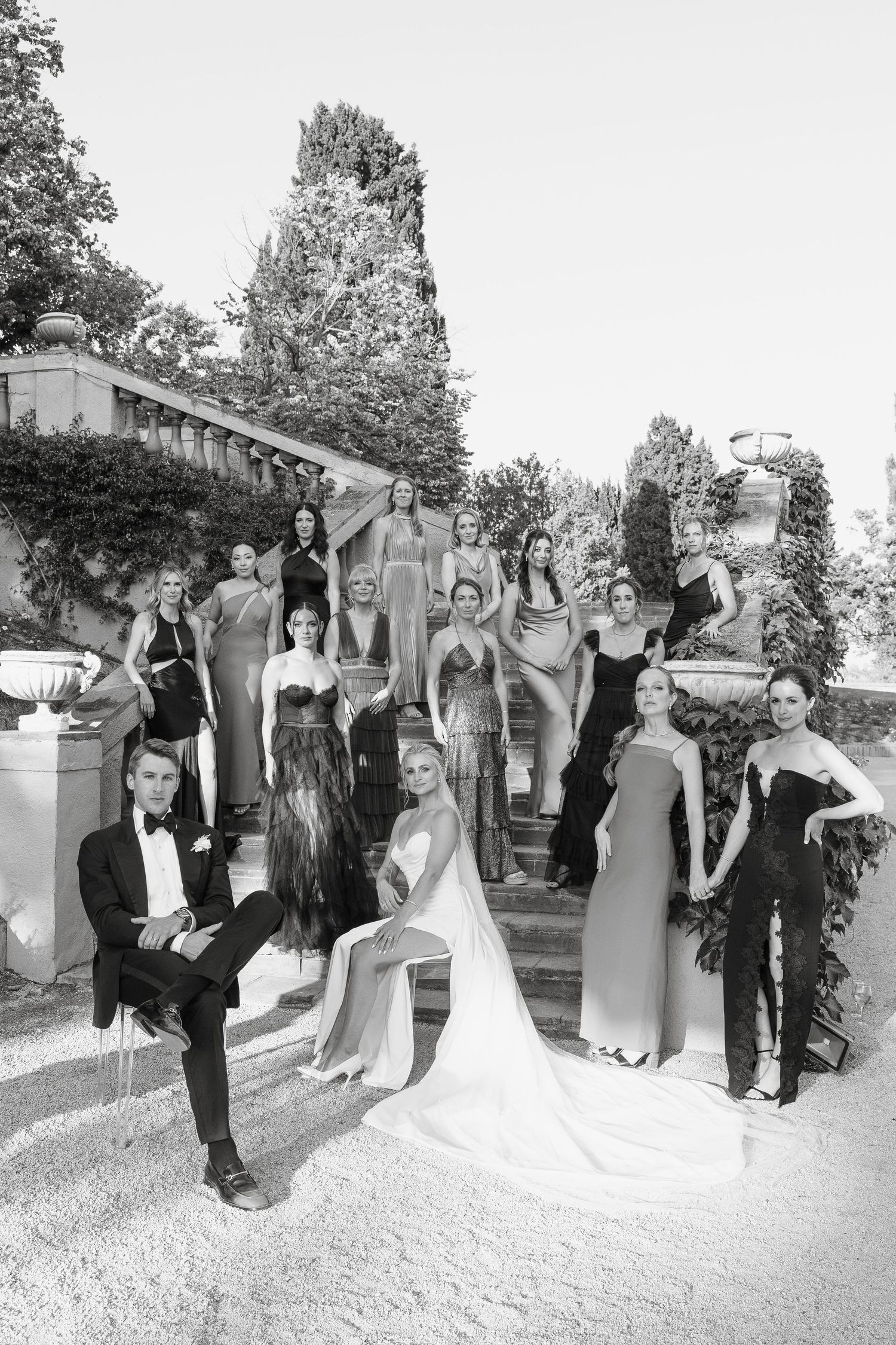 Black and white portrait of wedding party arranged on outdoor stone steps.
