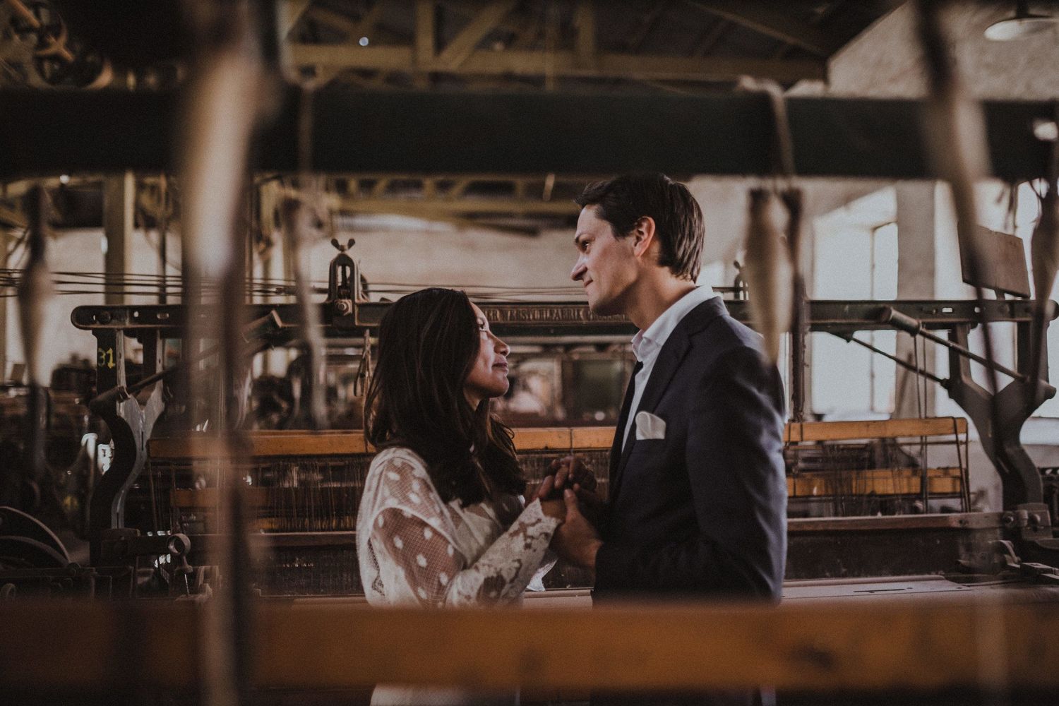 A romantic couple shares an intimate moment in an industrial vintage setting with machinery and warm lighting.