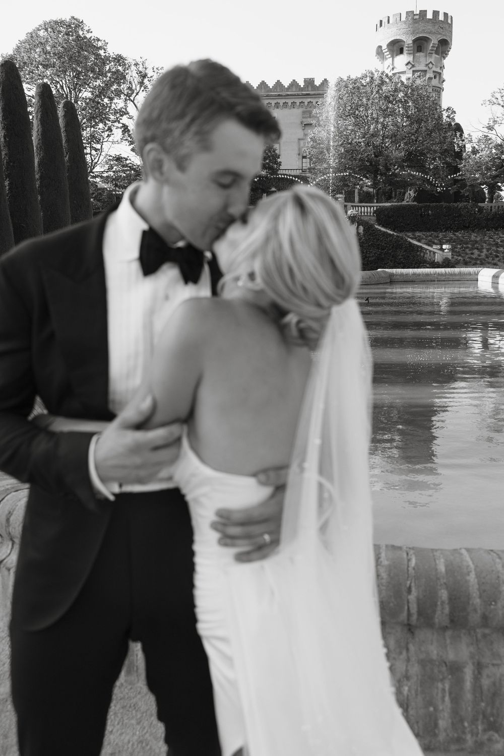 Wedding couple shares romantic moments near a castle with turrets in the background.
