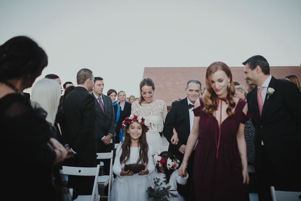 Wedding guests in formal attire standing during outdoor ceremony.