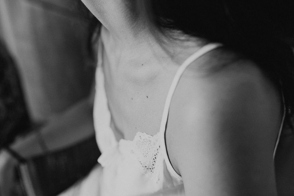 Close up detail of white lace dress strap and delicate embellishment in black and white.