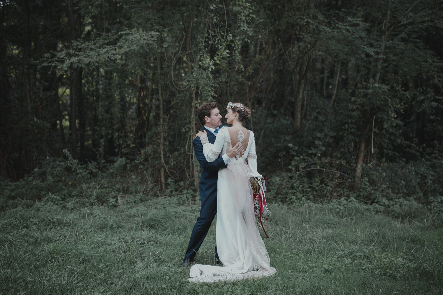Intimate wedding portrait in a moody forest setting with vintage-inspired dress.