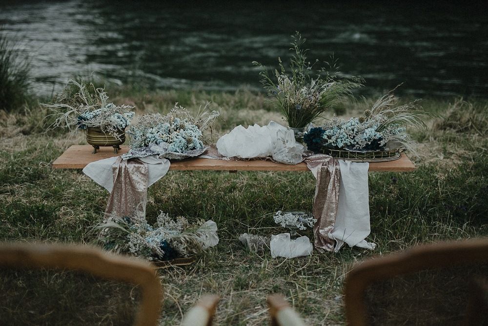 Rustic wooden bench decorated with blue and white florals near water.