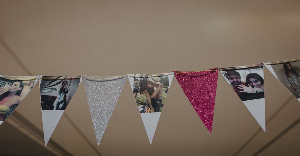 Decorative bunting with alternating patterns of floral, polka dot, and solid triangular flags hangs against a beige wall.