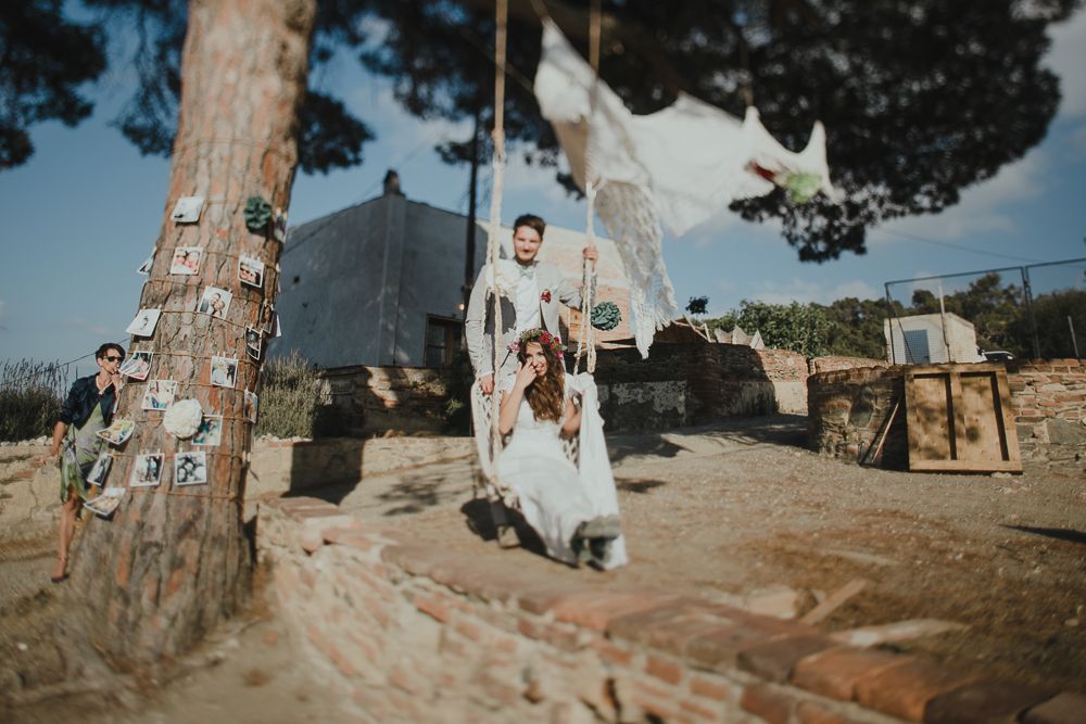 Artistic wedding photo with couple and white fabric flowing between trees in outdoor setting.