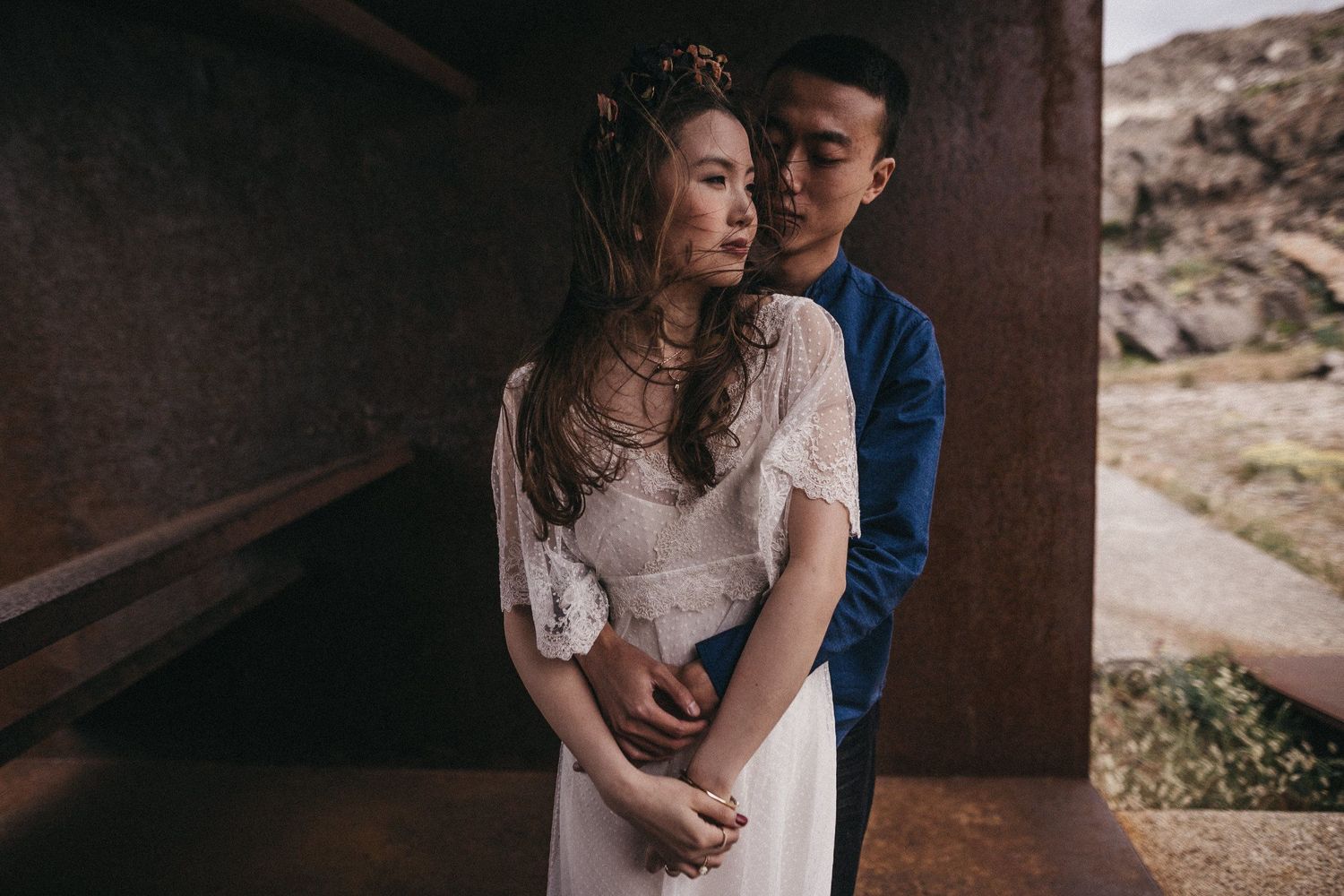 A tender embrace between two people in a concrete lookout with coastal views.