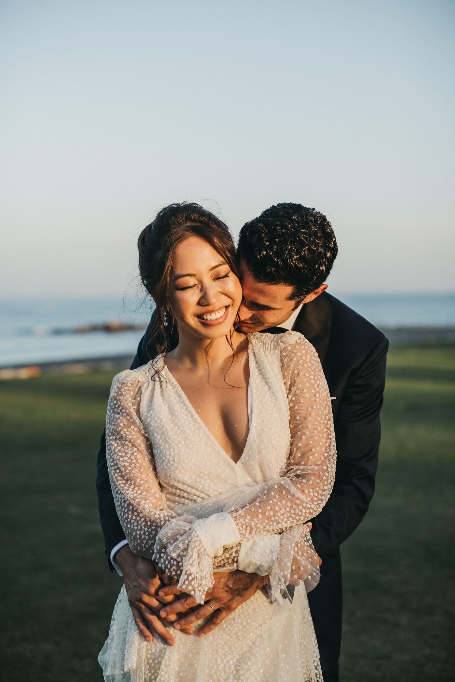 A couple shares intimate moments in a field during golden hour.