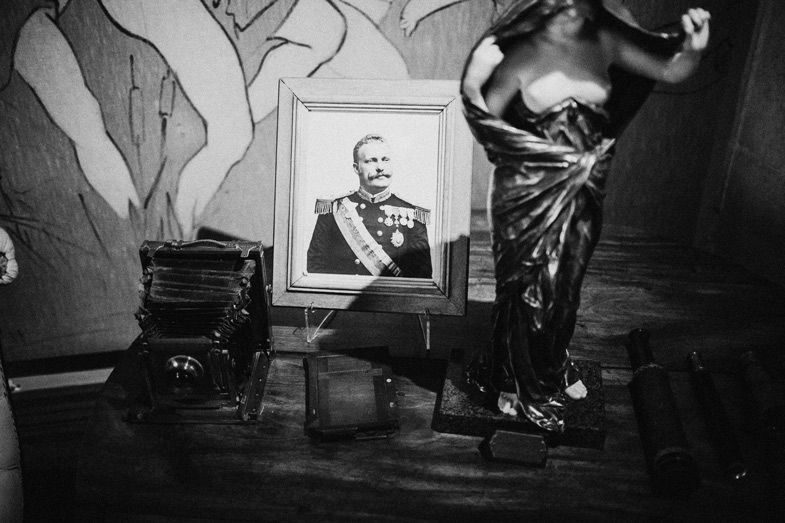 Vintage black and white photograph showing a portrait and antique furniture in a dark room.