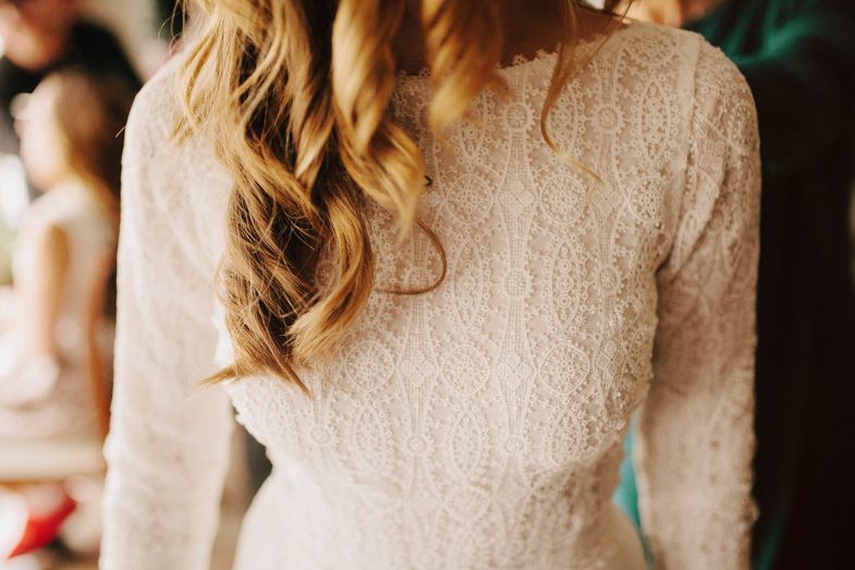 Detail shot of white lace long-sleeved wedding dress with intricate patterns.