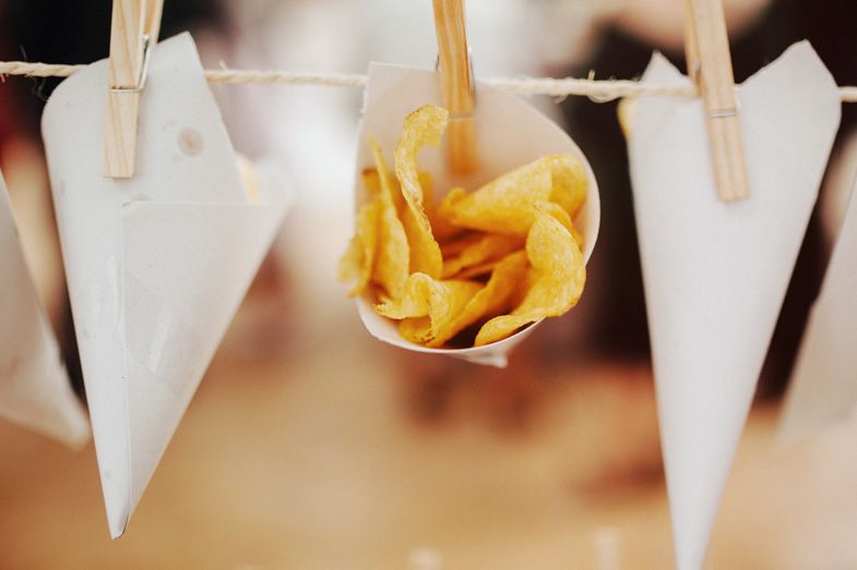 Paper cones filled with golden potato chips hanging from a display.