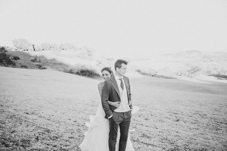 Two people stand together on a hillside path in a black and white scenic landscape.
