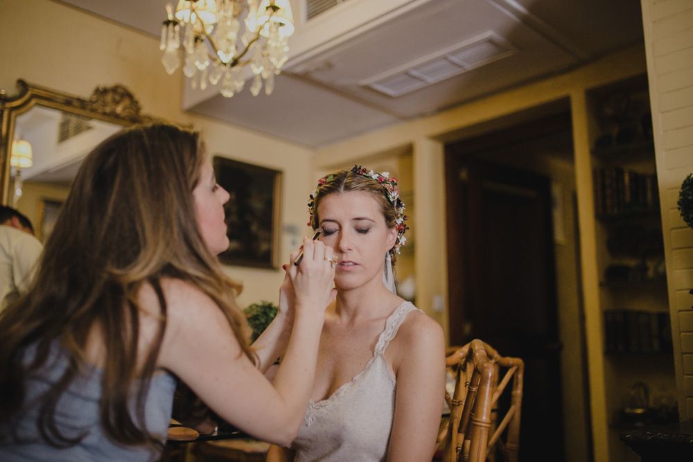 Wedding day makeup application in an elegant room with chandelier.