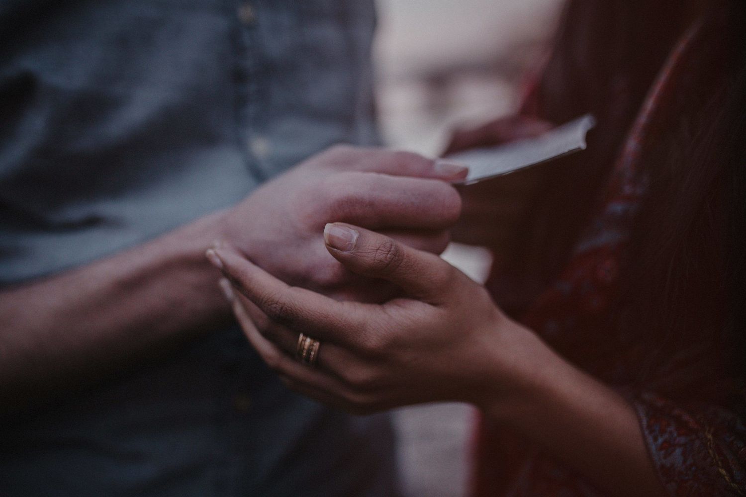 Close-up of hands exchanging rings during a tender moment.