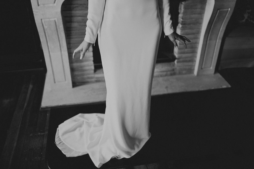 Detail of flowing white dress against dark wooden flooring.