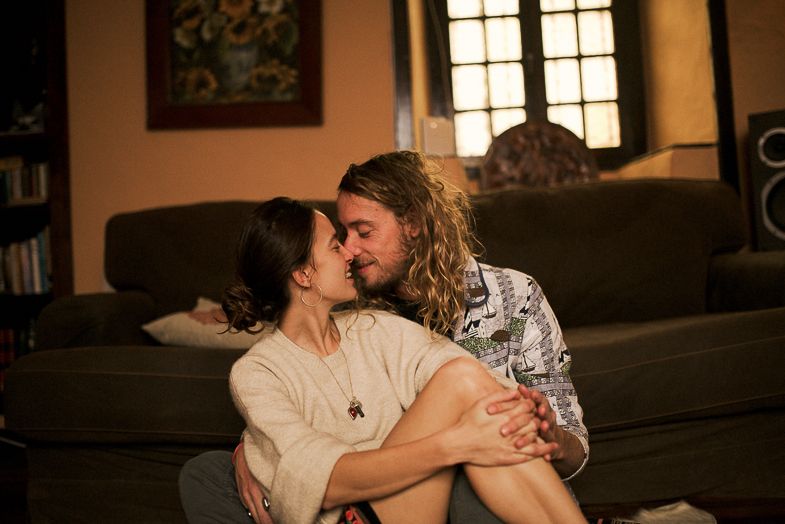 Intimate moment captured in golden hour lighting with bookshelves in background.