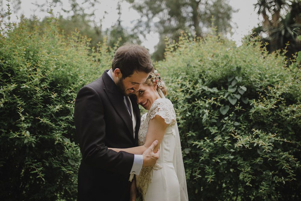 Intimate moment between newlyweds in a garden setting with natural greenery.