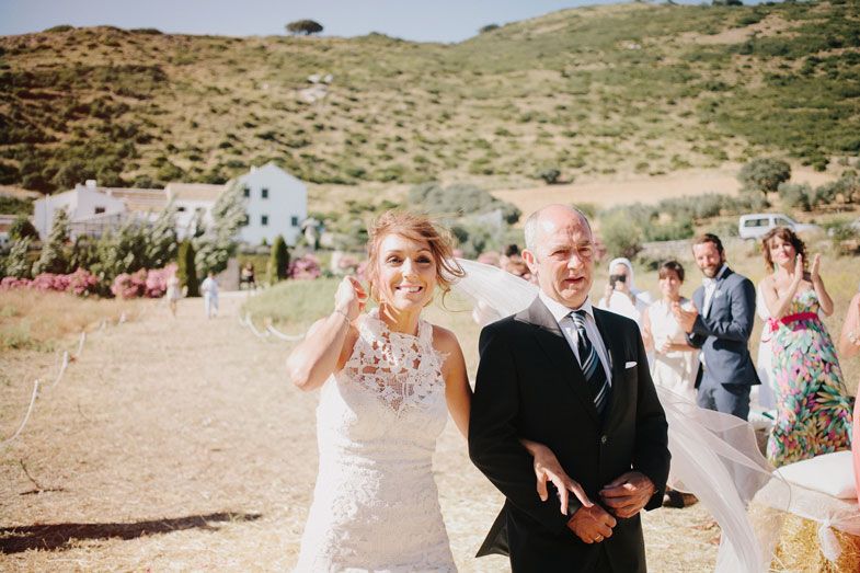 Wedding celebration on a hillside with white buildings and mountains in the distance.