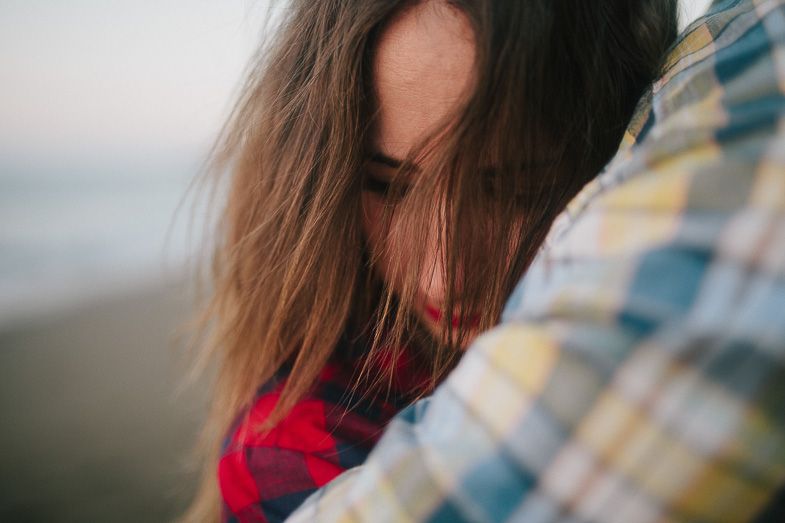 Close-up shot of a couple in casual wear sharing an intimate moment at the beach.