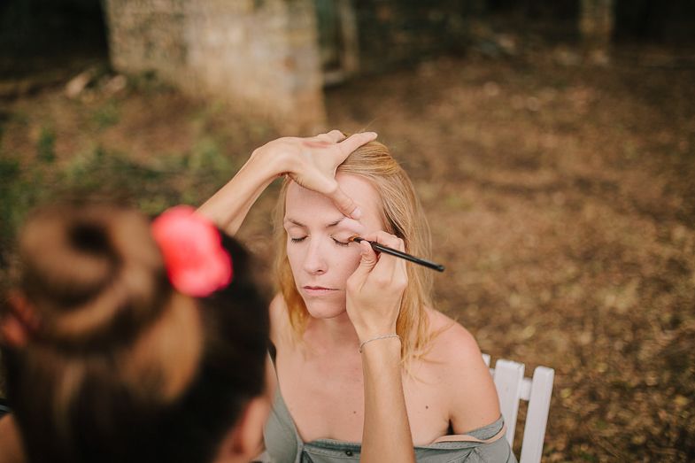 Professional makeup application being performed outdoors with natural lighting.