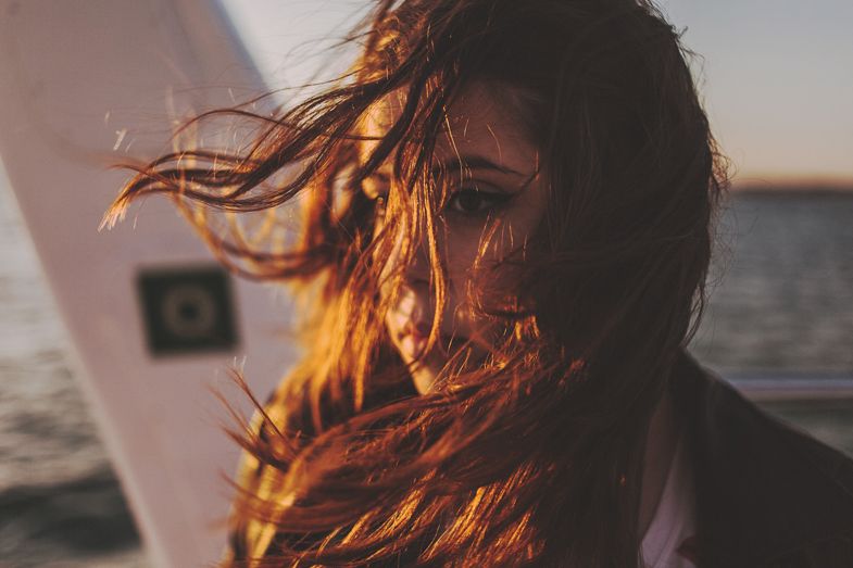 Hair blowing in the wind against an ocean backdrop at golden hour.