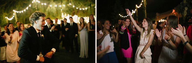 Wedding guests dancing and celebrating on an outdoor dance floor illuminated by string lights.