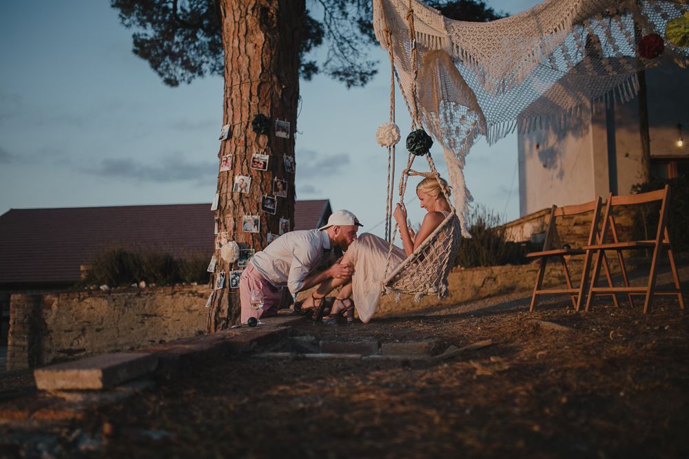 A romantic sunset picnic scene with lace decor and people relaxing on a hillside under a tree.