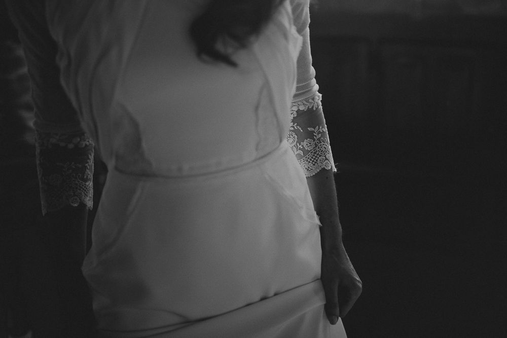 Intimate black and white photo focusing on the lace details of a wedding dress.