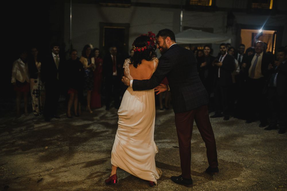 A couple shares an intimate first dance at their wedding reception while guests watch from the sidelines.