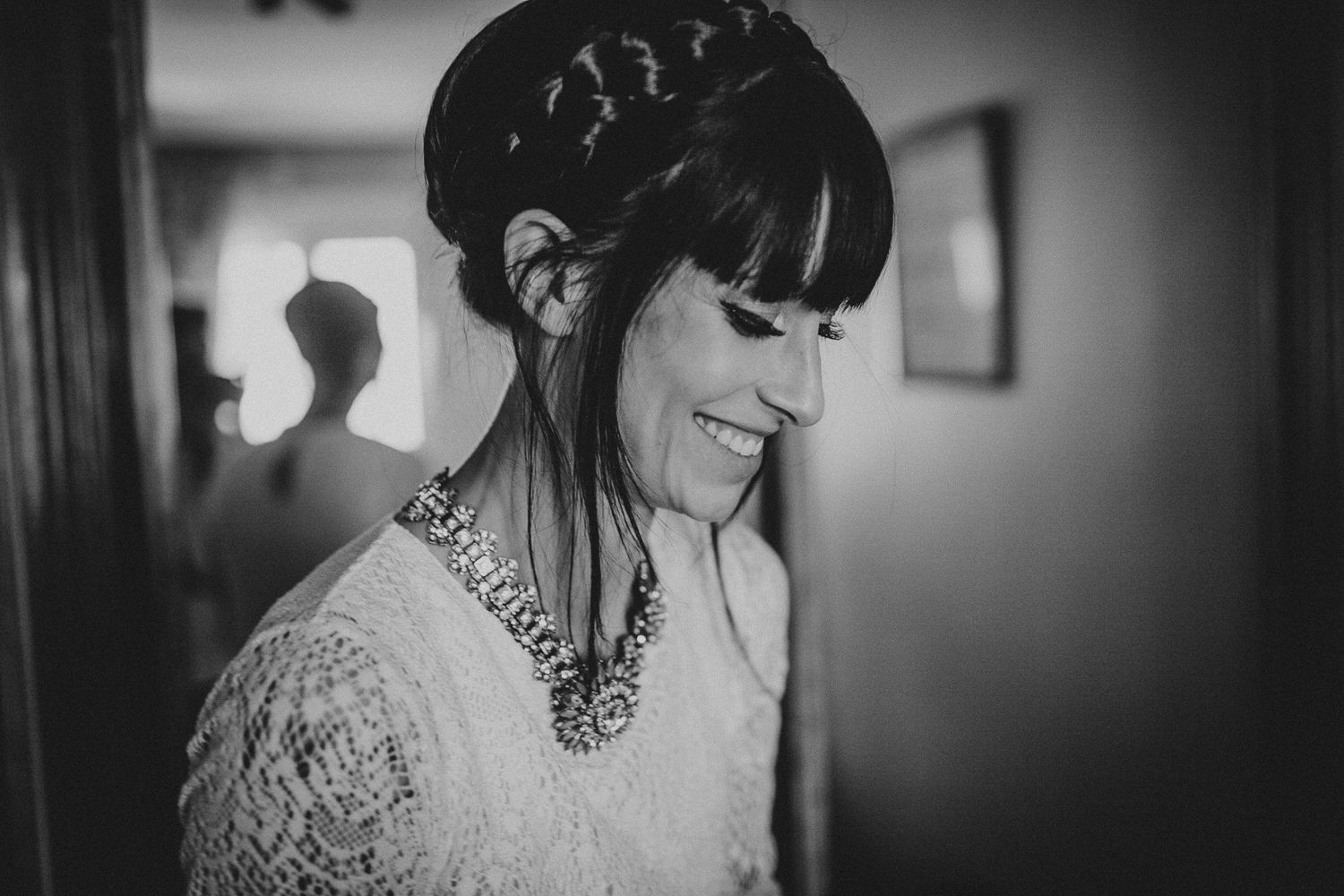 Black and white photo showing joyful expression while wearing lace and statement necklace.