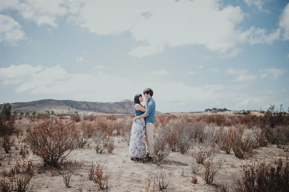 A romantic desert photoshoot with mountains and scrubland in the background.