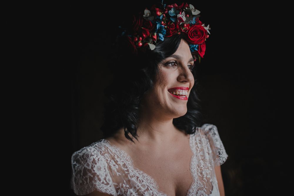 A vintage-inspired bridal portrait featuring a floral crown with red roses against dark background.