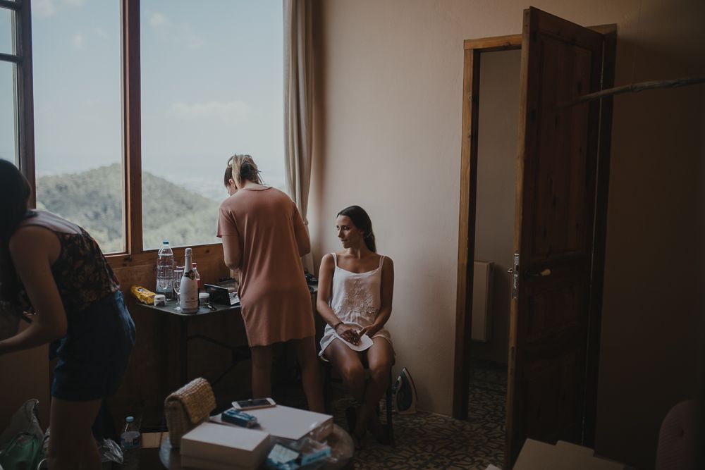 People getting ready in a sunlit room with mountain views through the window.