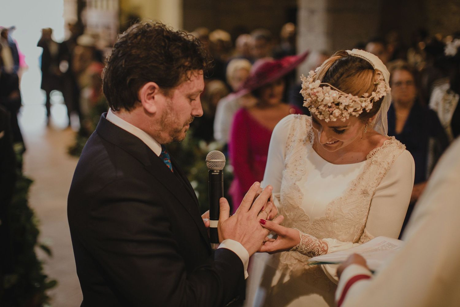 Wedding ceremony with exchange of rings in historic stone church interior.