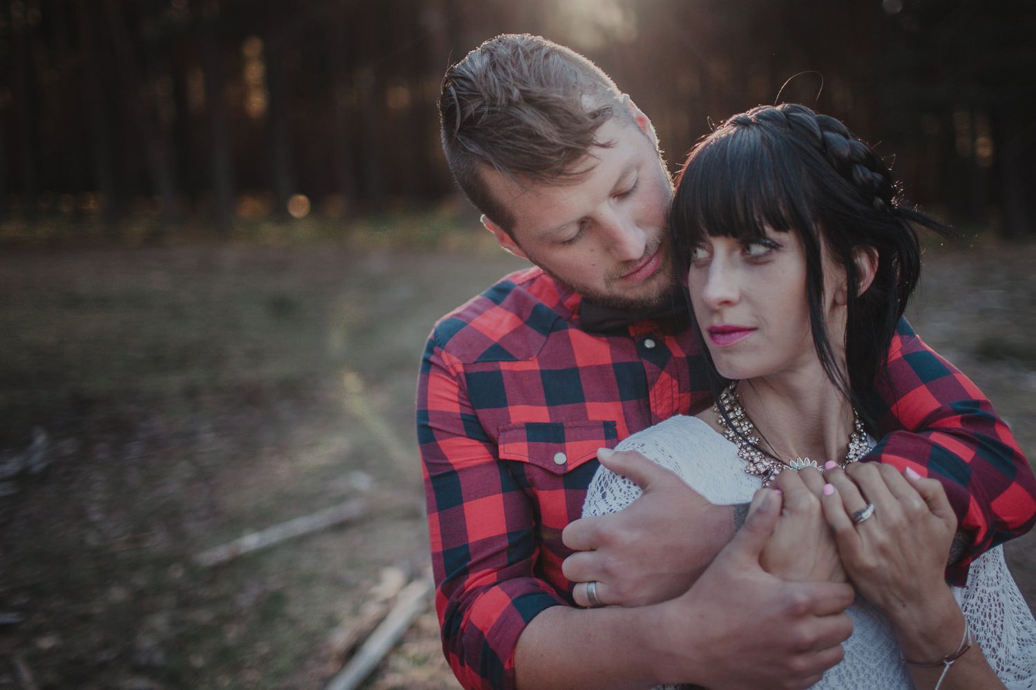 Intimate portrait of a couple embracing in a forest during golden hour.