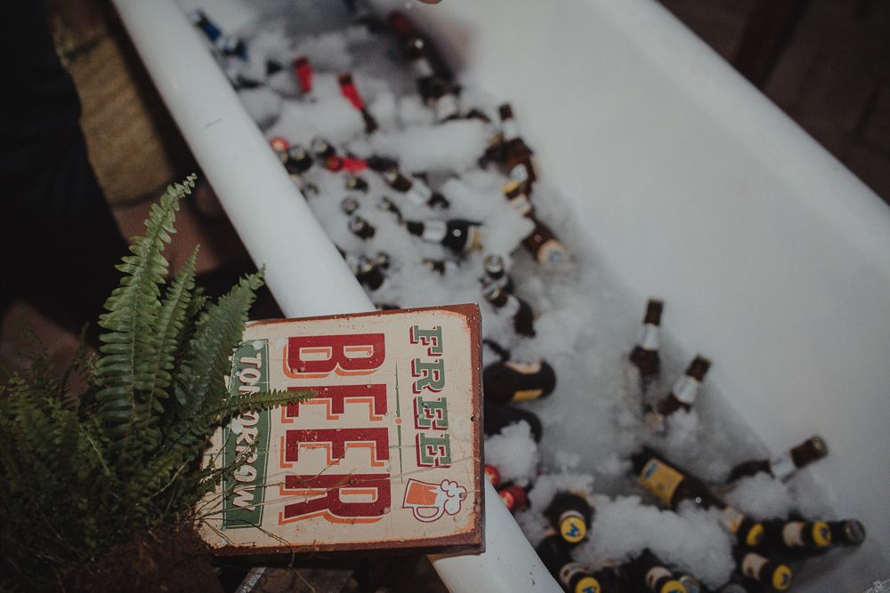 Vintage beer sign surrounded by ferns and scattered bottle caps in snow.