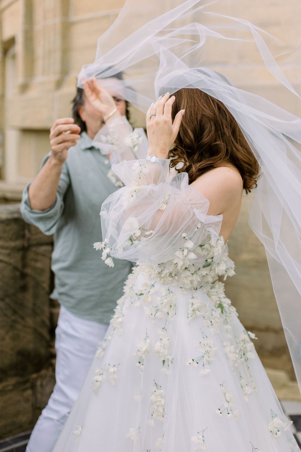 Playful sequence showing white wedding dress with floral details flowing in the wind.