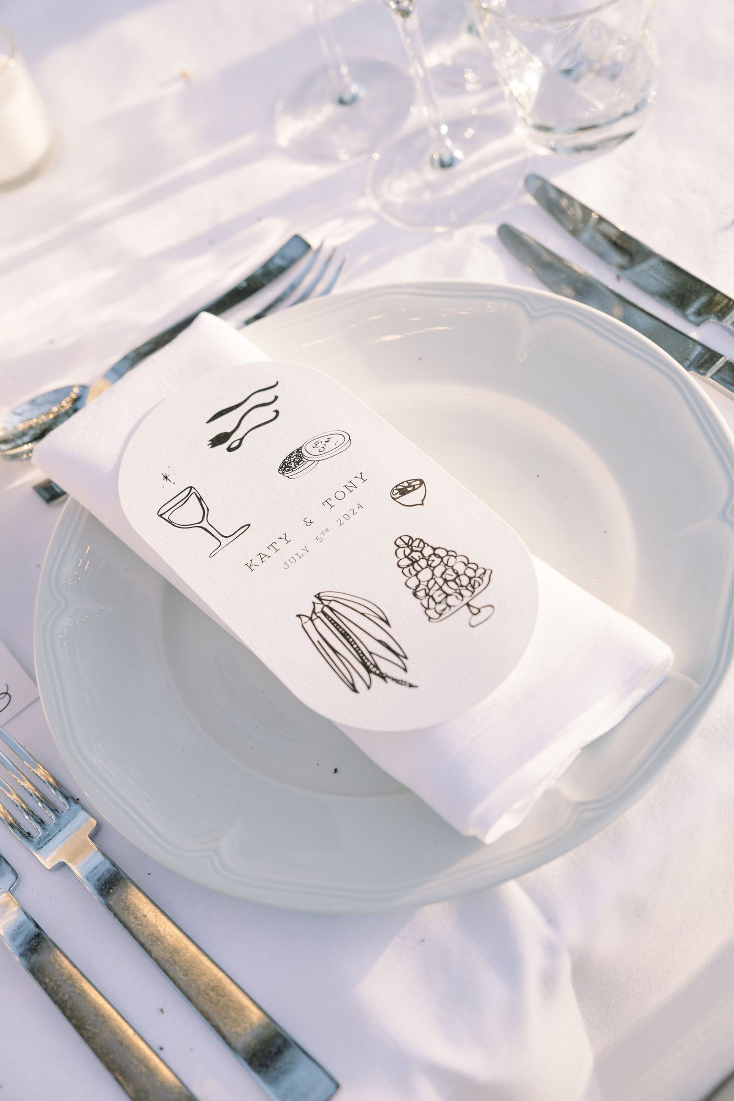 Wedding menu card with simple line drawings placed on white dinner plate.