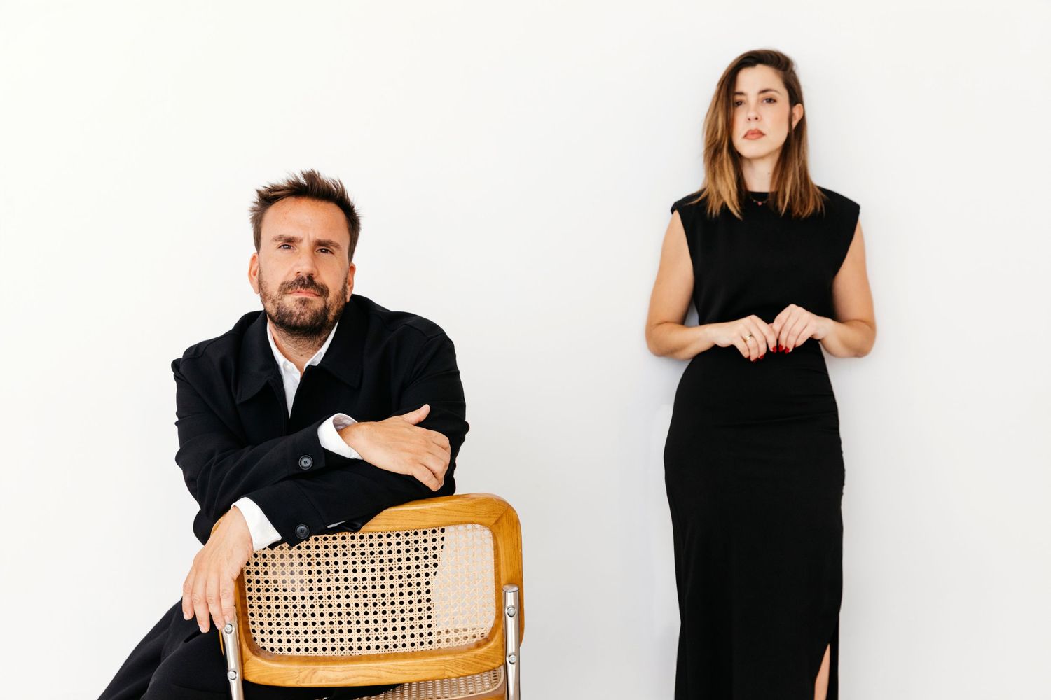 A series of black and white portraits showing people seated on wooden chairs against a white background.
