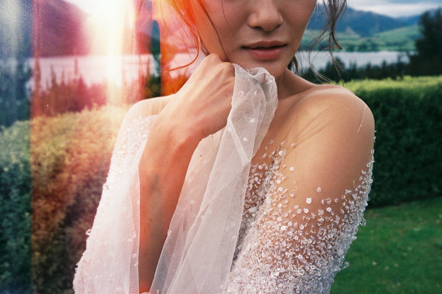 Detailed shot of sheer wedding dress sleeve with scattered pearl embellishments.
