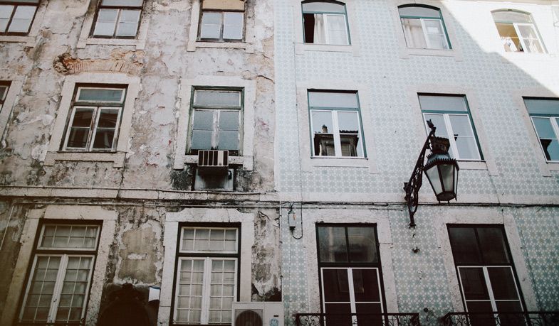 Window washer cleaning the exterior of a tiled building in Portugal.