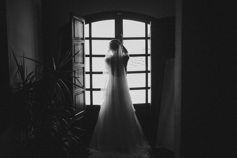 Silhouette of a wedding dress against a window in dramatic black and white.