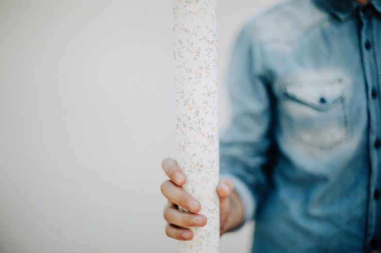 Close-up of hand reaching for white textured surface against light blue denim shirt.