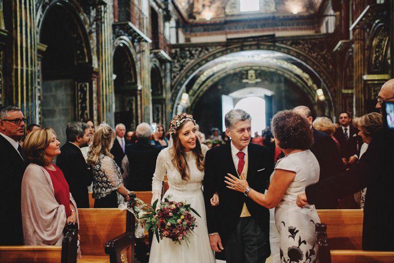 Wedding ceremony in a grand church interior with guests gathered in wooden pews.
